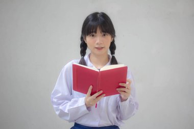 Asya Taylandlı lise öğrencisi üniforması. Güzel kız bir kitap okumuş.