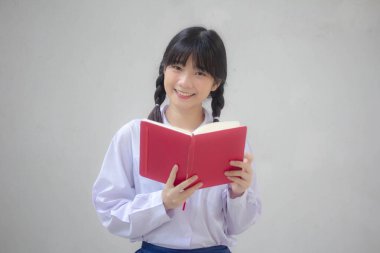 Asya Taylandlı lise öğrencisi üniforması. Güzel kız bir kitap okumuş.