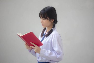 Asya Taylandlı lise öğrencisi üniforması. Güzel kız bir kitap okumuş.