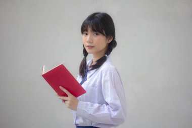 Asya Taylandlı lise öğrencisi üniforması. Güzel kız bir kitap okumuş.