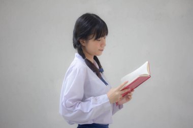 Asya Taylandlı lise öğrencisi üniforması. Güzel kız bir kitap okumuş.