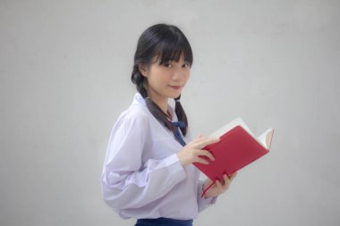 Asya Taylandlı lise öğrencisi üniforması. Güzel kız bir kitap okumuş.