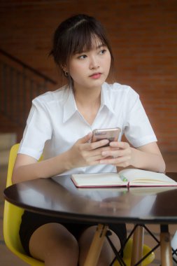 Taylandlı yetişkin öğrenci üniformasının portresi. Akıllı telefonunu kullanan güzel bir kız.