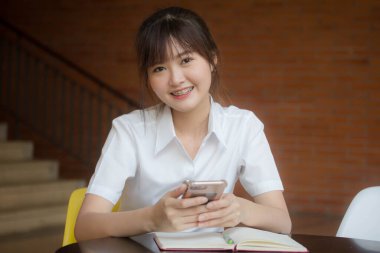 Taylandlı yetişkin öğrenci üniformasının portresi. Akıllı telefonunu kullanan güzel bir kız.