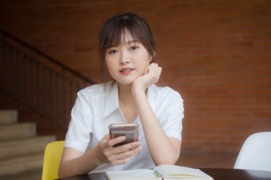 Taylandlı yetişkin öğrenci üniformasının portresi. Akıllı telefonunu kullanan güzel bir kız.