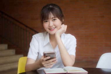 Taylandlı yetişkin öğrenci üniformasının portresi. Akıllı telefonunu kullanan güzel bir kız.