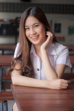 Taylandlı yetişkin öğrenci üniforması güzel kız rahatla ve gülümse.