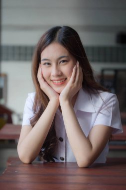 Taylandlı yetişkin öğrenci üniforması güzel kız rahatla ve gülümse.