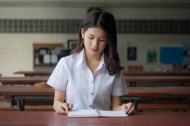 Taylandlı yetişkin üniversite üniforması güzel kız kırmızı kitabı okuyor.