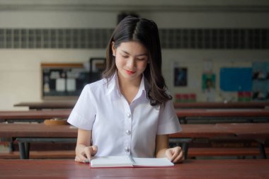 Taylandlı yetişkin üniversite üniforması güzel kız kırmızı kitabı okuyor.