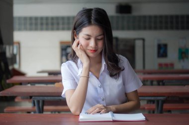 Taylandlı yetişkin üniversite üniforması güzel kız kırmızı kitabı okuyor.