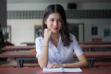 Taylandlı yetişkin üniversite üniforması güzel kız kırmızı kitabı okuyor.