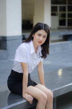 Taylandlı yetişkin öğrenci üniforması güzel kız rahatla ve gülümse.