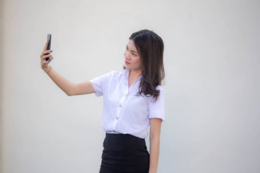 Yetişkin öğrenci üniforması güzel kız akıllı telefonuyla selfie çekiyor.