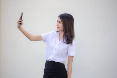 Yetişkin öğrenci üniforması güzel kız akıllı telefonuyla selfie çekiyor.