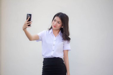 Yetişkin öğrenci üniforması güzel kız akıllı telefonuyla selfie çekiyor.