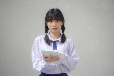 Taylandlı liseli üniforması güzel kız tabletini kullanıyor.