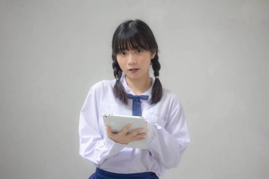 Taylandlı liseli üniforması güzel kız tabletini kullanıyor.