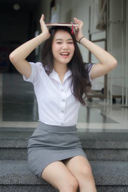 Taylandlı yetişkin öğrenci üniforması güzel kız rahatla ve gülümse.