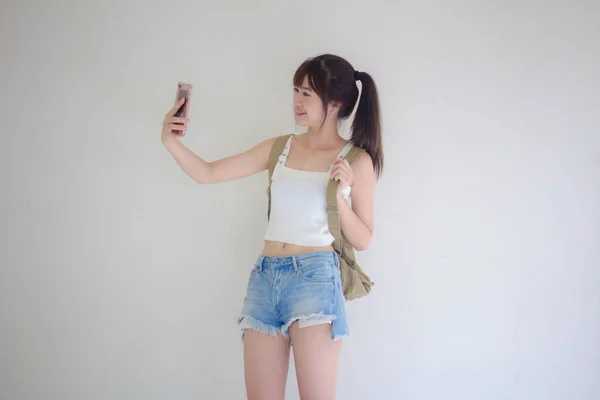 美しいですタイの女の子観光客スコティッシュホワイトシャツブルージーンズ使用して彼女のスマートフォンSelfie — ストック写真