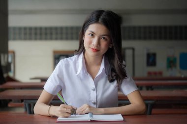 Taylandlı yetişkin üniversite üniforması güzel kız kırmızı kitabı okuyor.