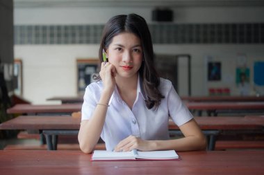 Taylandlı yetişkin üniversite üniforması güzel kız kırmızı kitabı okuyor.