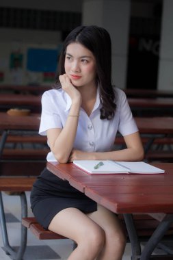 Taylandlı yetişkin üniversite üniforması güzel kız kırmızı kitabı okuyor.