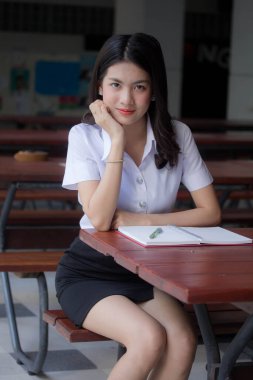 Taylandlı yetişkin üniversite üniforması güzel kız kırmızı kitabı okuyor.