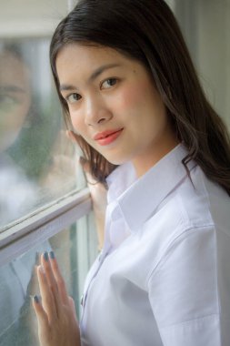 Taylandlı yetişkin öğrenci üniforması güzel kız rahatla ve gülümse.