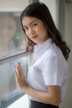 Taylandlı yetişkin öğrenci üniforması güzel kız rahatla ve gülümse.