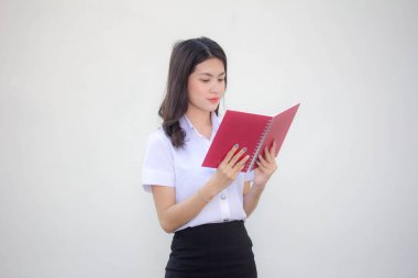 Taylandlı yetişkin üniversite üniforması güzel kız kırmızı kitabı okuyor.