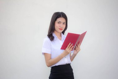 Taylandlı yetişkin üniversite üniforması güzel kız kırmızı kitabı okuyor.