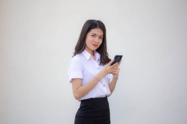 Yetişkin öğrenci üniforması. Akıllı telefonunu kullanan güzel bir kız.