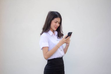 Yetişkin öğrenci üniforması. Akıllı telefonunu kullanan güzel bir kız.