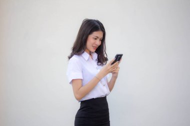 Yetişkin öğrenci üniforması. Akıllı telefonunu kullanan güzel bir kız.