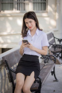 Taylandlı yetişkin öğrenci üniforması güzel kız rahatla ve gülümse.