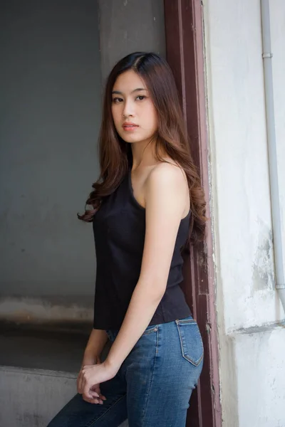 泰国人的画像中国成年人漂亮的女孩黑色衬衫蓝色牛仔裤放松微笑 — 图库照片