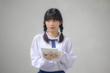 Taylandlı liseli üniforması güzel kız tabletini kullanıyor.