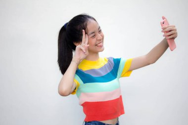 Asia Thai ergen tişörtü güzel kız akıllı telefonuyla selfie çekiyor.