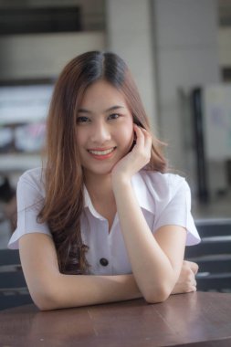 Taylandlı yetişkin öğrenci üniforması güzel kız rahatla ve gülümse.