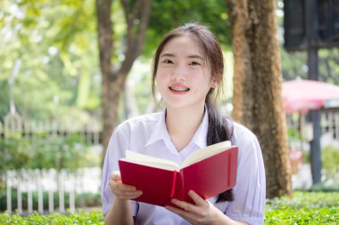 Asya Taylandlı lise öğrencisi üniforması. Güzel kız bir kitap okumuş.