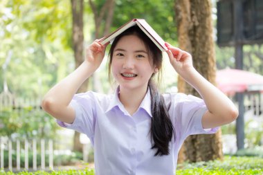 Asya Taylandlı lise öğrencisi üniforması. Güzel kız bir kitap okumuş.