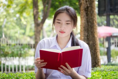 Asya Taylandlı lise öğrencisi üniforması. Güzel kız bir kitap okumuş.