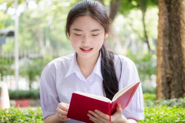 Asya Taylandlı lise öğrencisi üniforması. Güzel kız bir kitap okumuş.