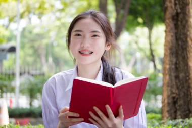 Asya Taylandlı lise öğrencisi üniforması. Güzel kız bir kitap okumuş.