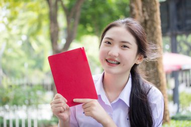 Asya Taylandlı lise öğrencisi üniforması. Güzel kız bir kitap okumuş.