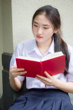 Asya Taylandlı lise öğrencisi üniforması. Güzel kız bir kitap okumuş.