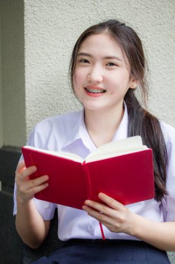 Asya Taylandlı lise öğrencisi üniforması. Güzel kız bir kitap okumuş.