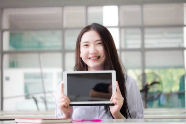 Portrait of thai high school student uniform beautiful girl using her tablet.