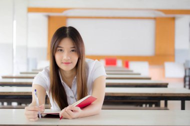 Taylandlı yetişkin öğrenci üniforması portresi. Kırmızı kitap okuyan güzel bir kız.